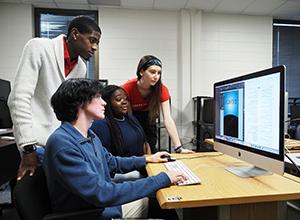 通信专业的学生在实习时一起看着电脑显示器.