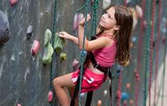 Young girl climbing on rock wall.