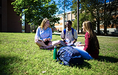 Three students sitting on ground at campus
